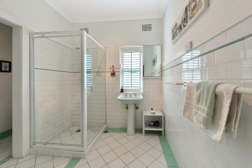 Un baño blanco con ducha y lavabo. en Woodford House of Leura, en Leura