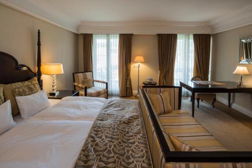a hotel room with a large bed and a desk at Falkensteiner Schlosshotel Velden – The Leading Hotels of the World in Velden am Wörthersee