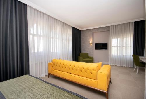 a living room with a yellow couch in a room at CONNECT THERMAL HOTEL in Ankara