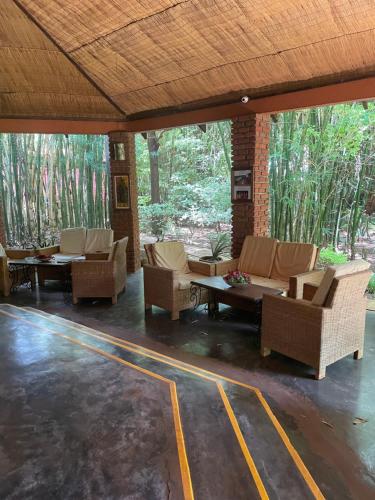 a patio with couches and tables and trees at Octagon Lodge in Karatu