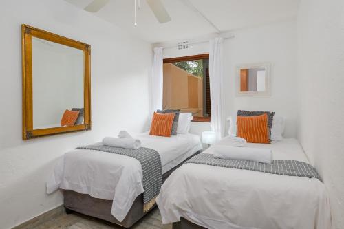 two beds in a white room with a mirror at San Lameer Villa 1914 - 2 Bedroom Classic - 4 pax - San Lameer Rental Agency in Southbroom