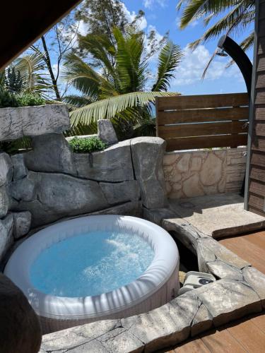 a hot tub in a stone wall next to a swimming pool at Ti case bord de mer in Saint-Benoît