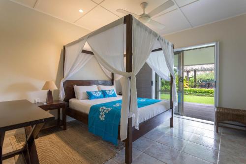1 dormitorio con cama con dosel y mesa en Muri Beach Villa, en Rarotonga