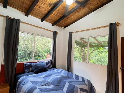 um quarto com uma cama e duas janelas em Olon Cabin em Olón