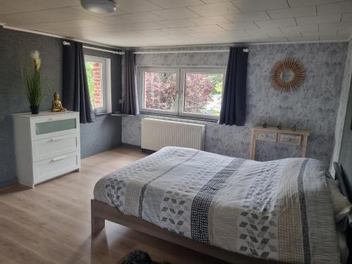 een slaapkamer met een bed en 2 ramen bij Maison de vacances aux portes des Fagnes in Hamoir