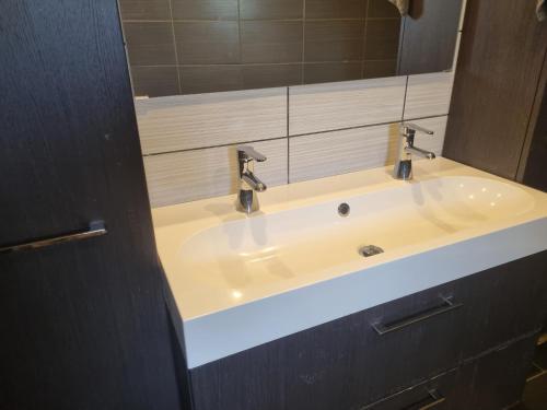 a bathroom sink with two faucets and a mirror at Maison de vacances aux portes des Fagnes in Hamoir
