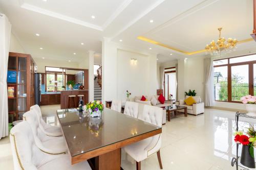 a dining room with a table and white chairs at Palm Villa Đà Lạt 5 - Luxury Villa khu Villa Đồi An Sơn in Da Lat
