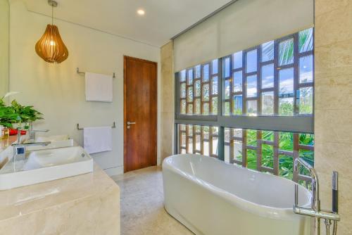 a bathroom with a tub and a sink and a window at Luxury Pool Villa Close To The Private Beach in Danang