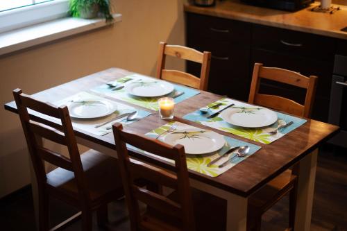 a wooden table with plates and silverware on it at NIENOVO - Apartament Kórnik niedaleko jeziora i widok na Arboretum in Kórnik