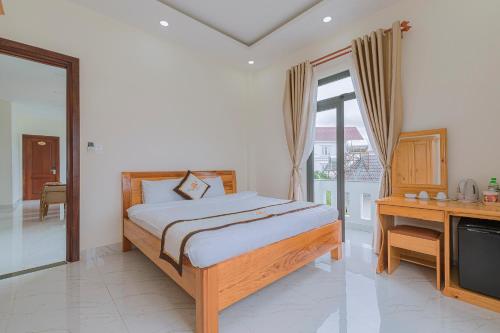 a bedroom with a bed and a desk and a television at ROSA VILLA & HOTEL Dalat in Da Lat
