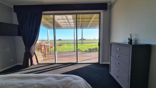 a bedroom with a large sliding glass door to a patio at Wheel chair & Pet Friendly Waterfront Retreat, 10 minutes to Phiilip Island, fireplace, wood supplied, WIFI wine & chocolates in Kilcunda