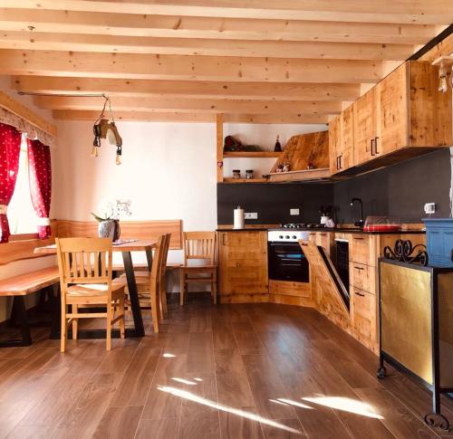 a kitchen with wooden cabinets and a dining table at Baita Alpenrose in Ugovizza