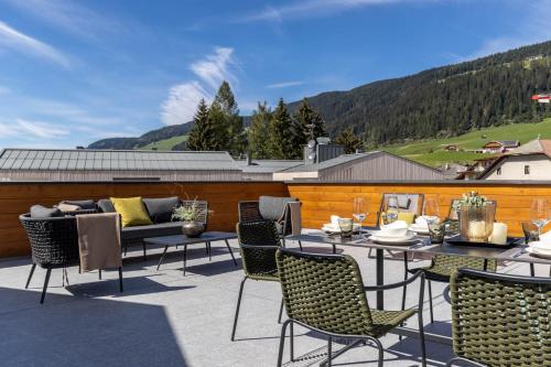 a patio with chairs and tables and a couch at Bellavista Apartment in Dobbiaco
