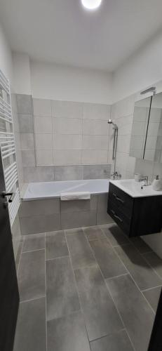 Baño blanco con bañera y lavamanos en Dotis Apartman Tata en Tata
