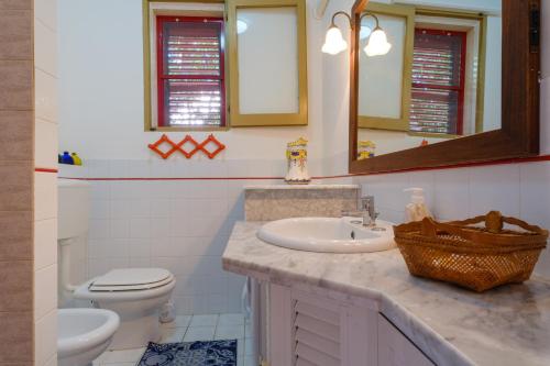 a bathroom with a sink and a toilet and a mirror at Villa Elena in Porto Cesareo