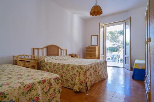 a bedroom with two beds and a sliding glass door at Villa Elena in Porto Cesareo