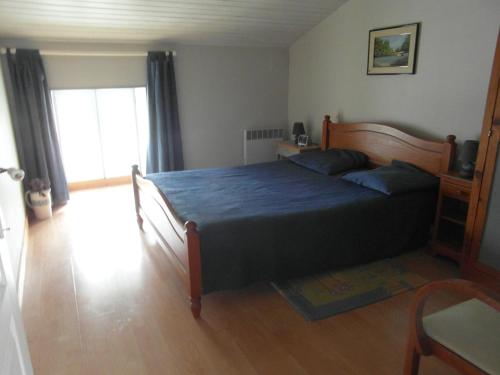 1 dormitorio con 1 cama grande con manta azul en GITE A LA FERME en Le Pin-Saint-Denis