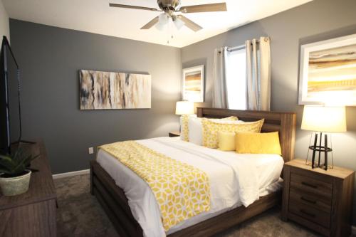 a bedroom with a bed with yellow pillows and a ceiling fan at Gorgeous 3Br Condo 10 min Disney, Golf Water Park in Kissimmee