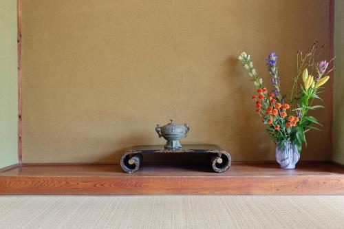 a table with a vase and flowers on it at AI/藍 in Kusatsu