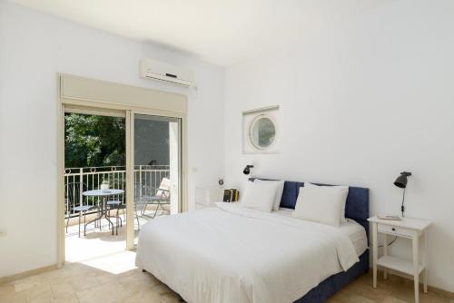 a white bedroom with a bed and a balcony at Adorable 2 bedrooms apt w Bomb Shelter next to the beach in Tel Aviv
