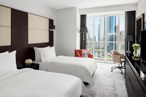 a hotel room with two beds and a window at Mövenpick Hotel Jumeirah Lakes Towers Dubai in Dubai