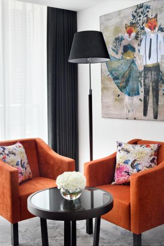 a living room with two orange chairs and a table at Mövenpick Hotel Jumeirah Lakes Towers Dubai in Dubai