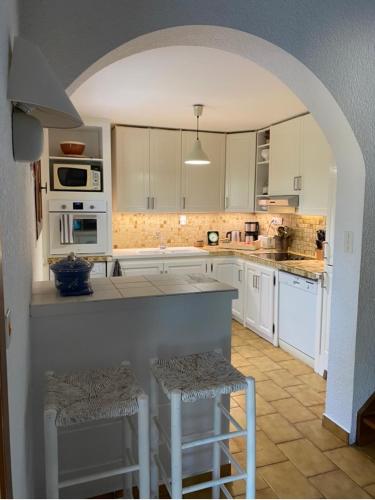 une cuisine avec des armoires blanches et un comptoir avec des tabourets dans l'établissement Villa au bord du Lac d'Esparron-de-Verdon, à Esparron-de-Verdon
