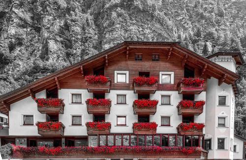 ein Gebäude mit Blumenkästen drauf mit einem Berg in der Unterkunft Alps Oriental Wellness HOTEL in Campodolcino