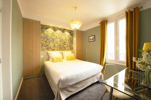 a bedroom with a bed and a painting on the wall at Hôtel des Batignolles in Paris
