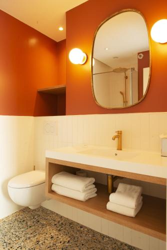 a bathroom with a sink and a toilet and a mirror at Hôtel des Batignolles in Paris