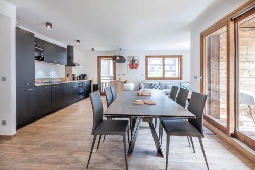 une cuisine et une salle à manger avec une table et des chaises en bois dans l'établissement Echo du Pleney B103, à Morzine
