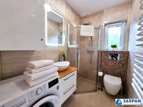 een badkamer met een douche, een wastafel en een toilet bij Perła Pomorza Mielno - 365PAM in Unieście