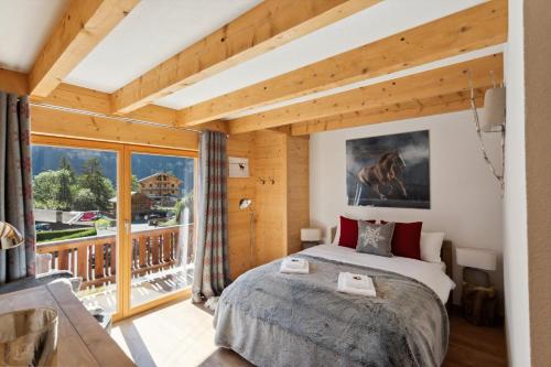 a bedroom with a large bed and a balcony at Chalet Haute Cime by Mrs Miggins in Champéry