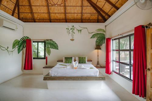 a bedroom with a bed with red curtains at Karaboon Wellness in Phitsanulok