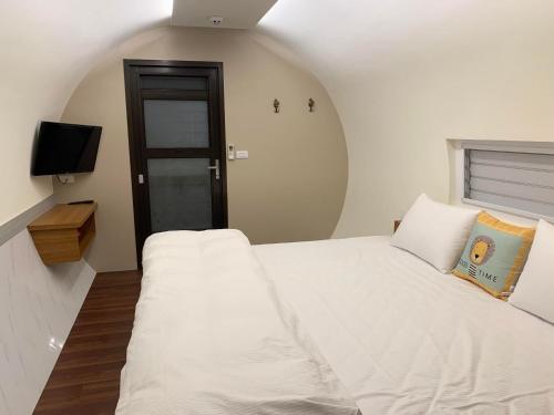 a bedroom with a white bed and a television at Star & Moon GUEST HOUSE in Puli
