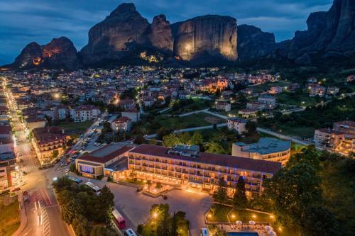 uma cidade à noite com montanhas ao fundo em Divani Meteora Hotel em Kalabaka