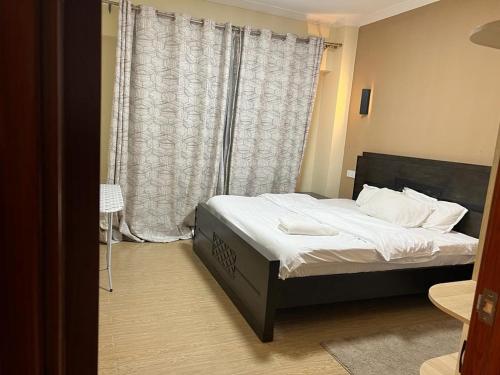 um quarto com uma cama e uma grande janela em Enzi Heights Apartment Block B em Nairobi