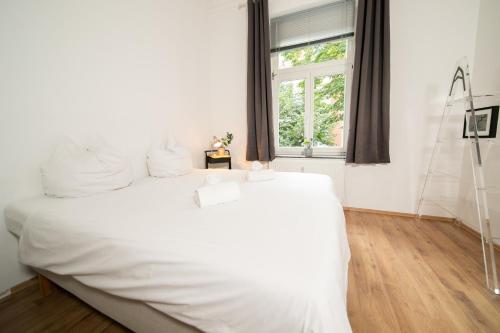 Cama blanca en habitación con ventana en WHITE 60 QM Apartment - Zentral - Balkon - Messe, en Düsseldorf