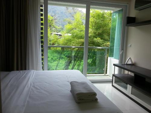 ein Schlafzimmer mit einem Bett und einem großen Fenster in der Unterkunft The Baycliff Residences in Patong Beach