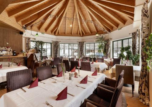 uma sala de jantar com mesas brancas e cadeiras com guardanapos vermelhos em Golf- und Sporthotel Moarhof em Walchsee