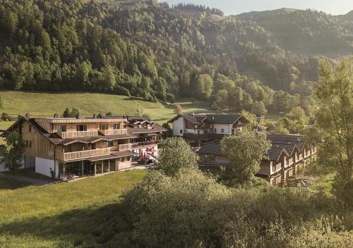 a group of buildings on a hill with trees at Golf- und Sporthotel Moarhof in Walchsee