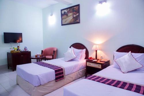 um quarto de hotel com duas camas e uma televisão em Meridian Hotel em Chittagong