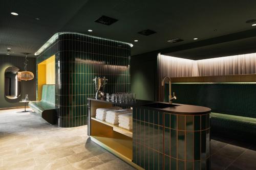 a bathroom with green walls and a counter with towels at Hotel Galántha in Eisenstadt