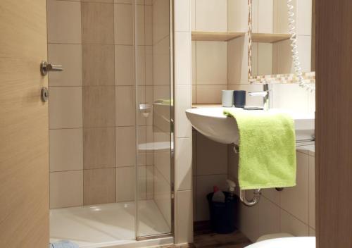 a bathroom with a glass shower door next to a sink at Ferienhaus Birgit - inklusive Eintritt Alpentherme Bad Hofgastein in Bad Hofgastein