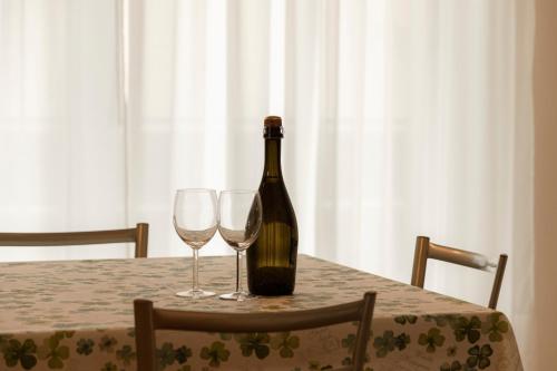 a bottle of wine sitting on a table with two glasses at HOLIDAY APARTMENTS GIULIA - Green in Pietramurata