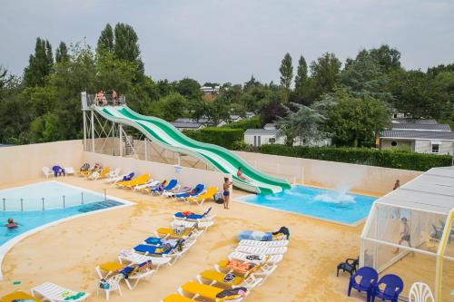 - une piscine avec toboggan, chaises et personnes dans l'établissement Camping De La Plage Bénodet - 400 mètres de La Plage, à Bénodet