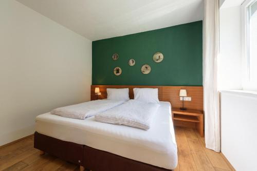 ペットイ・アム・アールベルクにあるAppartement Ackerliの緑の壁のベッドルーム1室(大型ベッド1台付)