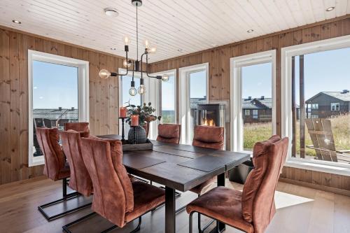 a dining room with a table and chairs and windows at Golsfjellet - Bualie, milevis med sykkelveier, fiske og vannaktivitet, ski inn/ut til alpinanlegg og langrennsløyper. in Gol