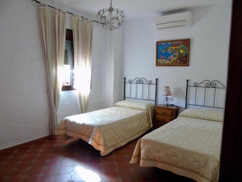 a bedroom with two beds and a chandelier at Balcón al Valle in El Gastor