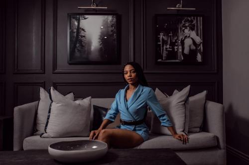 a woman in a blue dress sitting on a couch at Seven Villa Hotel & Spa in Johannesburg